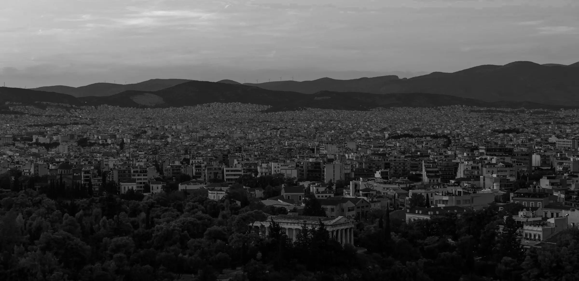 Panoramic view of Athens with ancient ruins, dense urban buildings, and hills