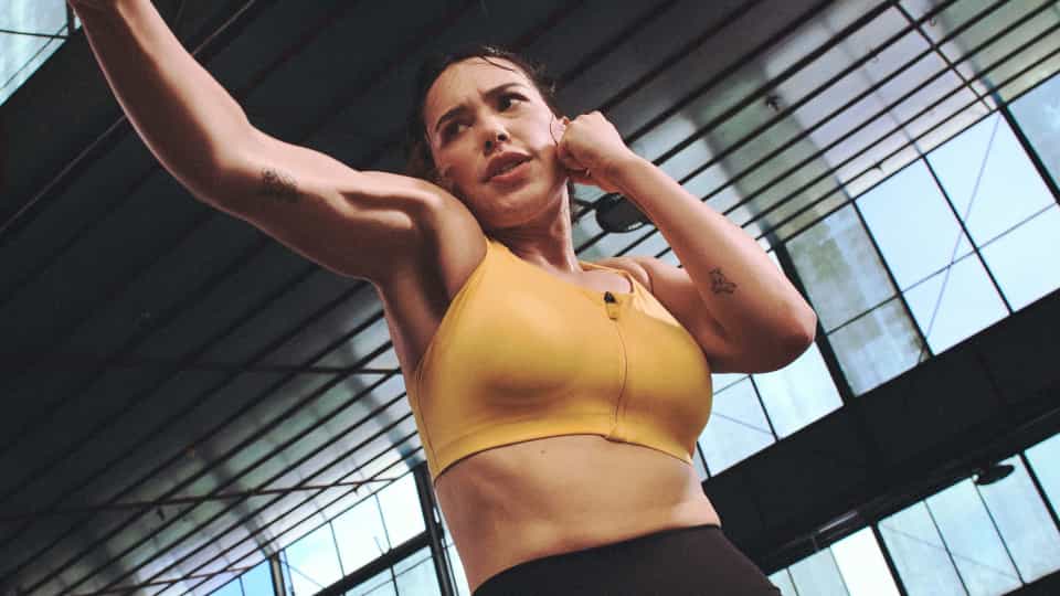 Person in a yellow sports top mid-punch during a workout