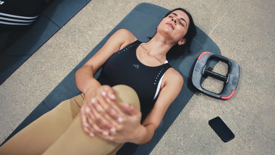 A person holding one knee toward the chest in a stretching position.
