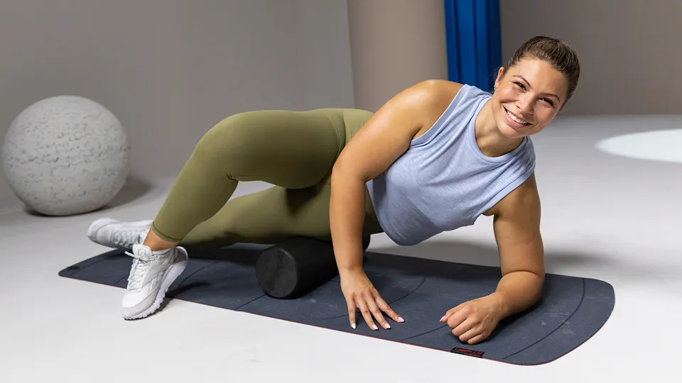 a person on a foam roller on side while lying on mat