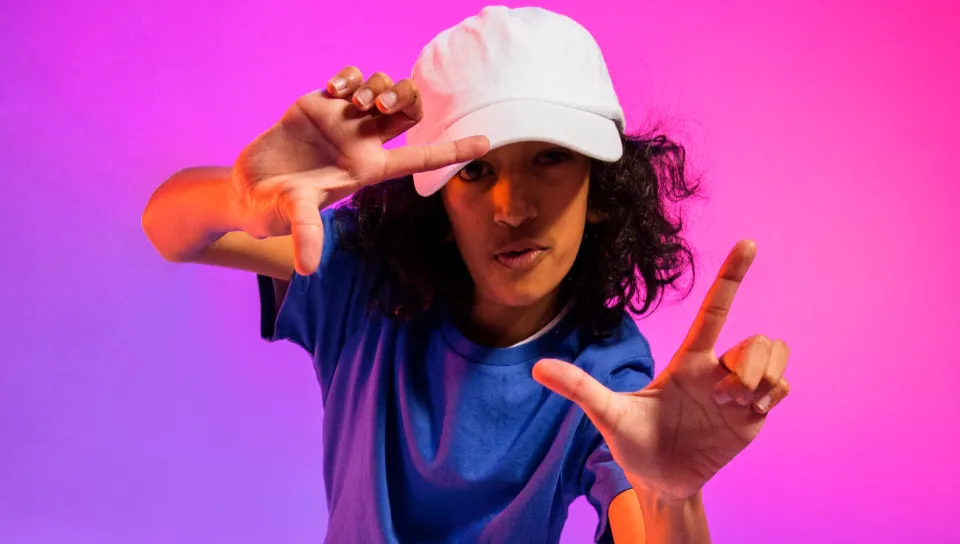 Person in blue shirt and white cap framing with hands