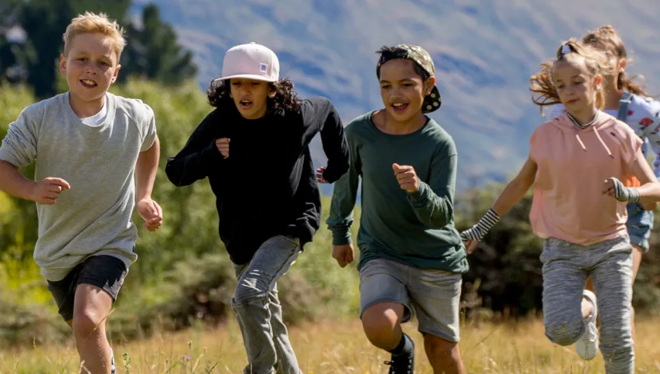 four children running in an open field
