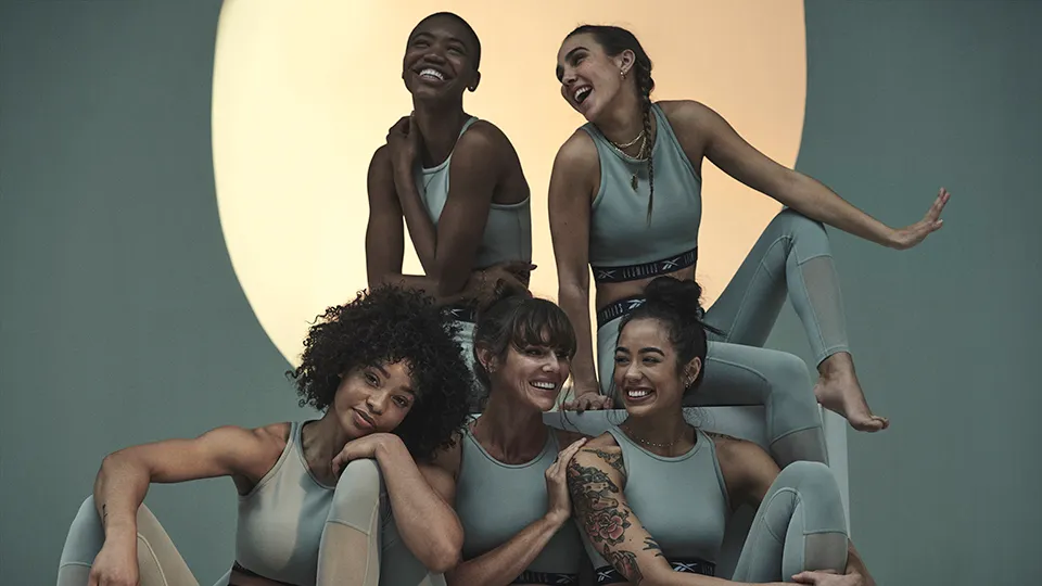 Group of women pose while wearing green fitness clpthes