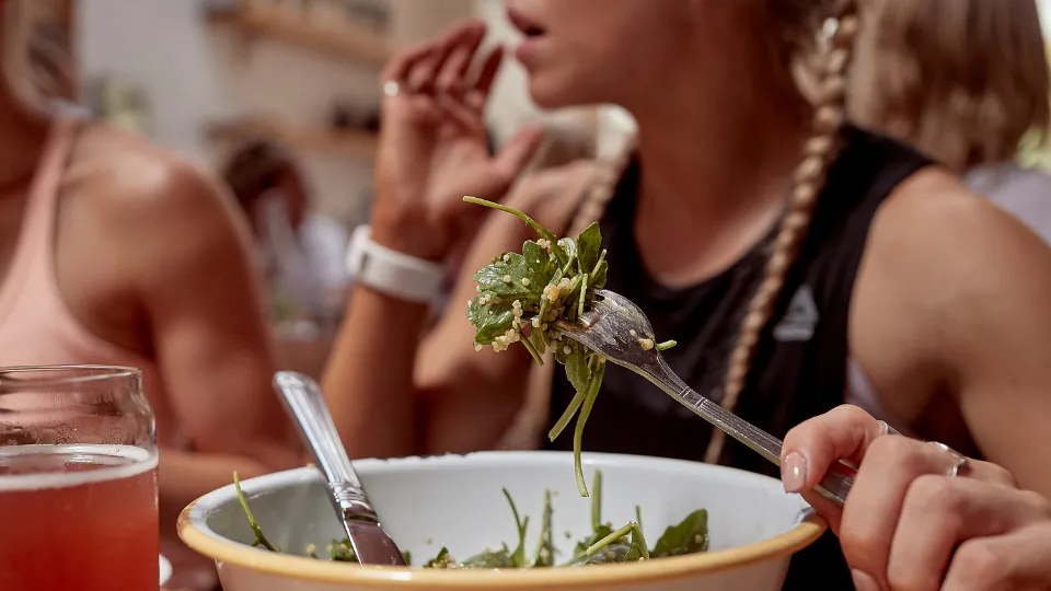 woman holding a fork eating salad