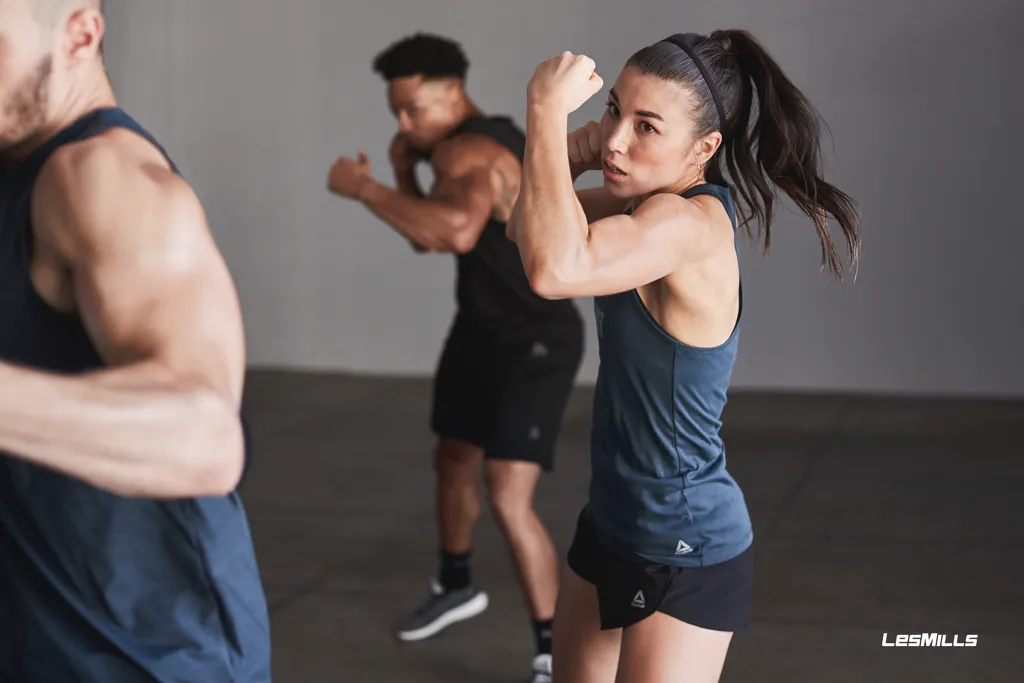 People in athletic gear performing boxing moves in a bright studio