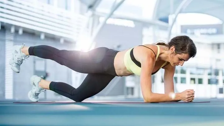 Person in plank position lifting one leg on a mat