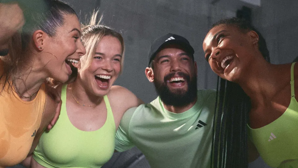 Four friends hugging and smiling after a workout.