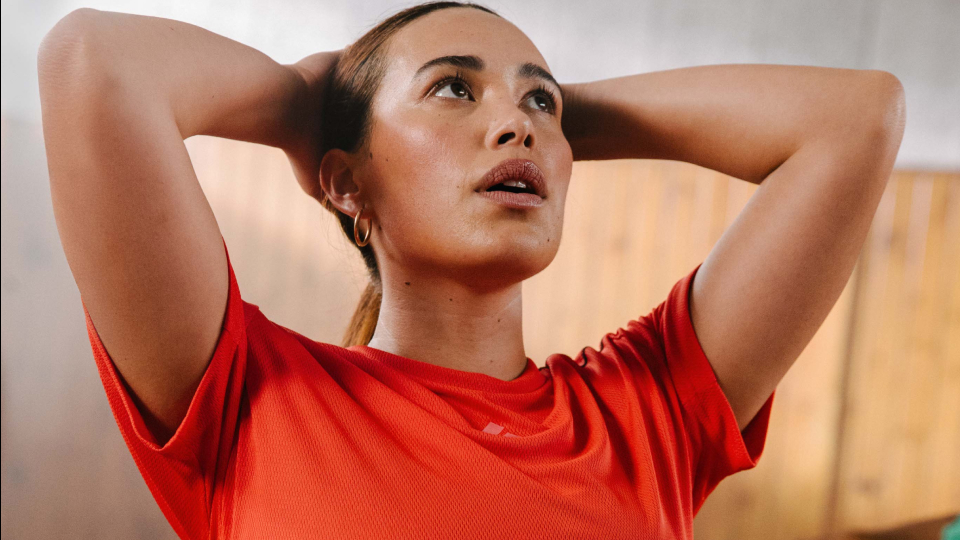 A woman looks contemplative in a red tee shirt