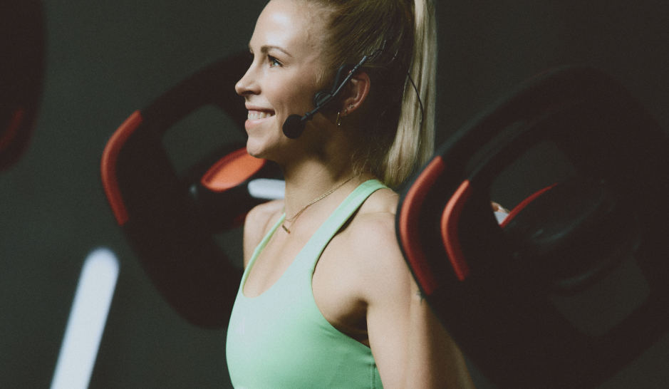 Blonde female fitness instructor with barbell on her back