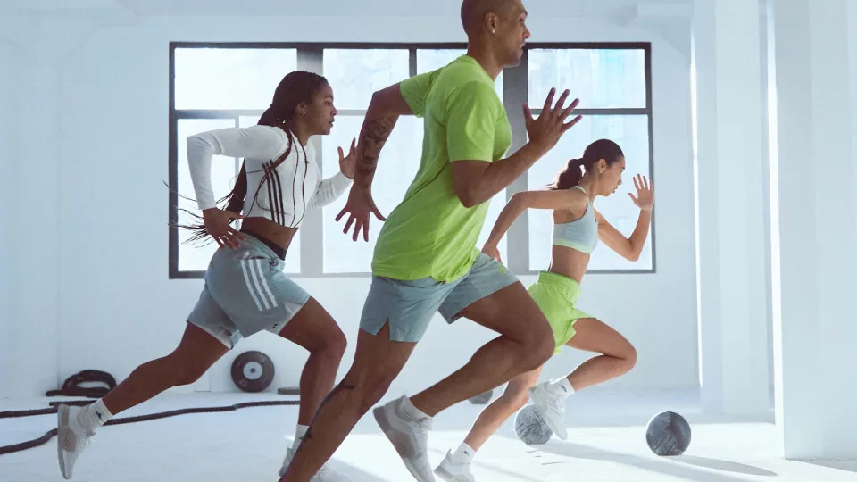 Three exercisers run indoors in a group workout