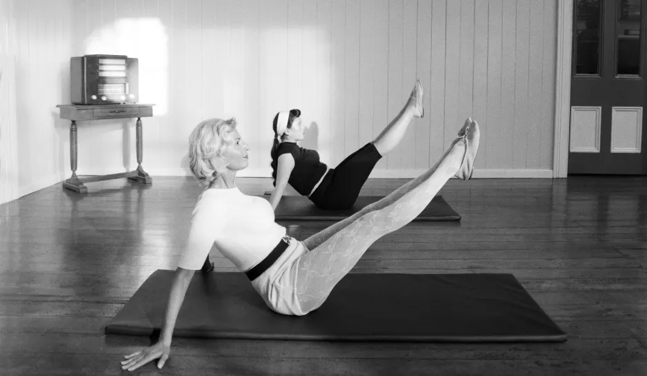 Stylish women doing Pilates on the floor