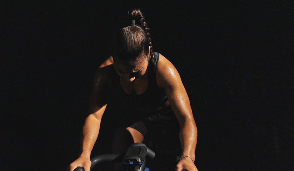 A women on an indoor cycle in a dark room