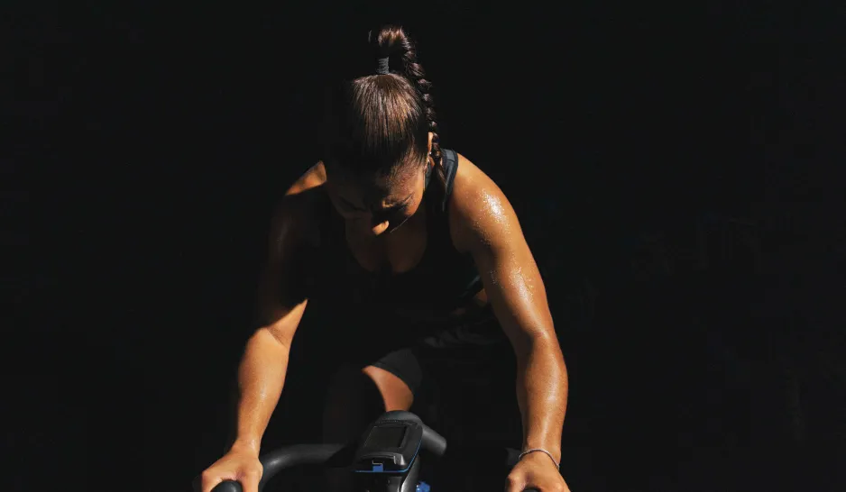 A women on an indoor cycle in a dark room