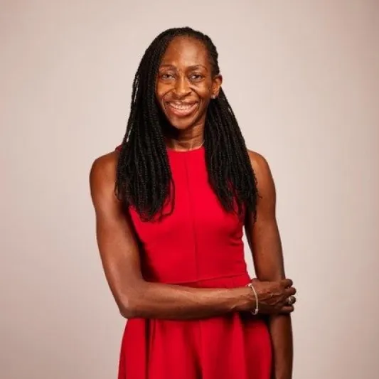 A woman poses in red dress with long dark braids
