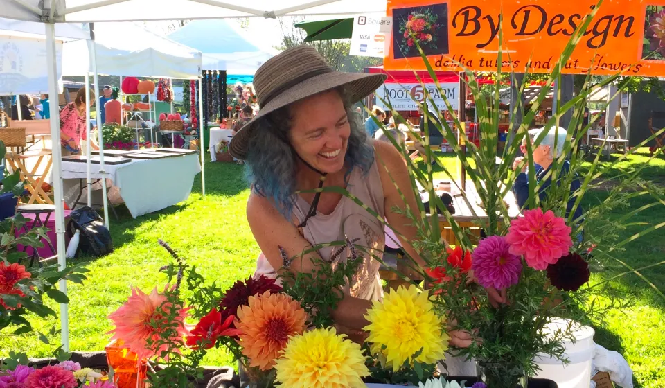 A woman in a sunhat selling dahlias