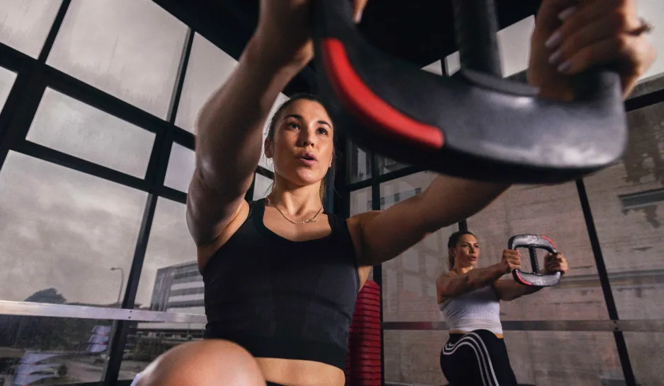 A girl lifts a weight plate in a industrial gym