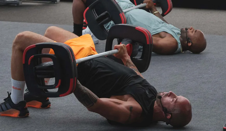 Two instructors training glutes doing hip bridges with barbells