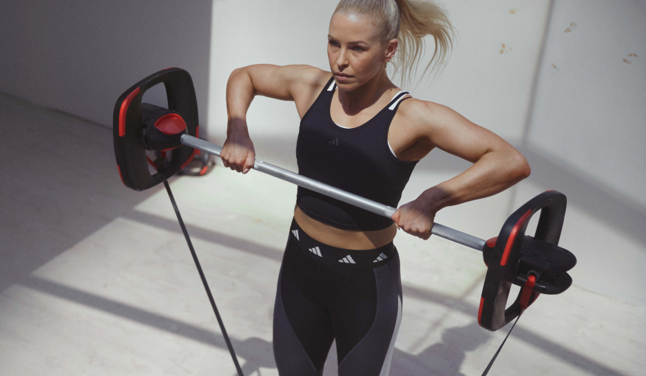 A blonde woman in black exercise gear lifts a barbell