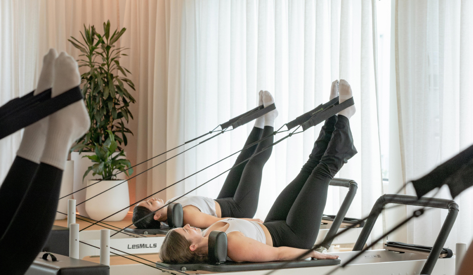 Feet in straps in a group reformer pilates class with sheer white curtains