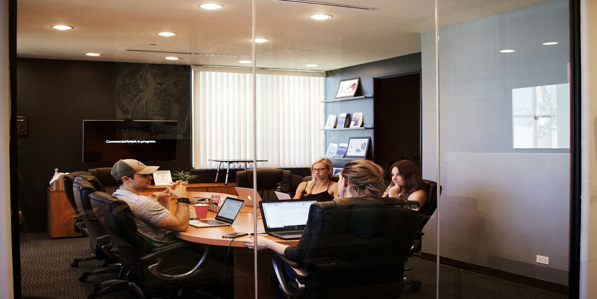 Australian business owner calculating employee retention bonus costs on calculator with team meeting in background