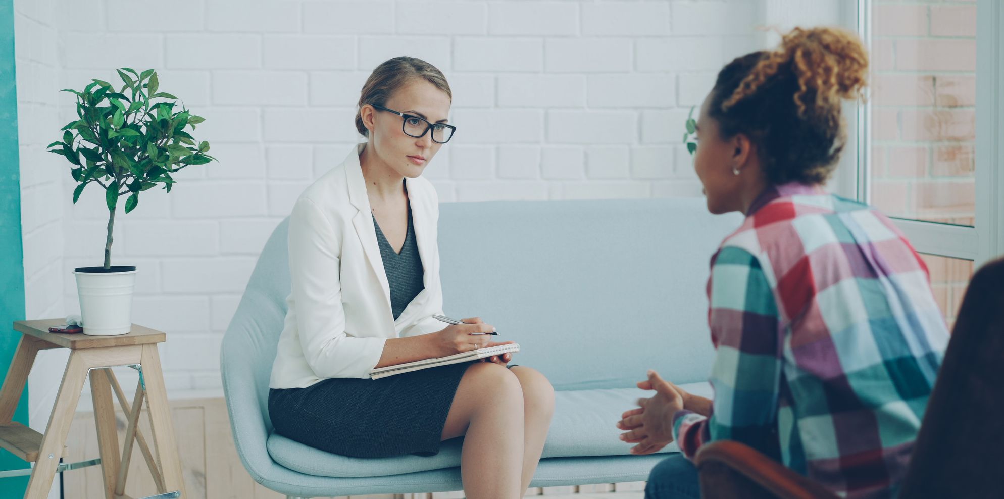 Psychologist taking notes during a counselling session with a client in a bright, modern practice room
