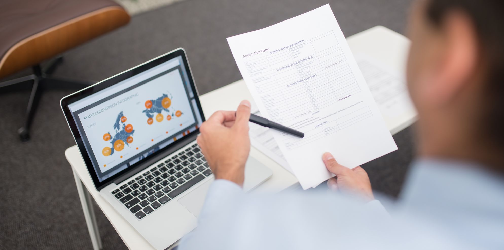 Business owner reviewing a printed application form beside a laptop showing charts