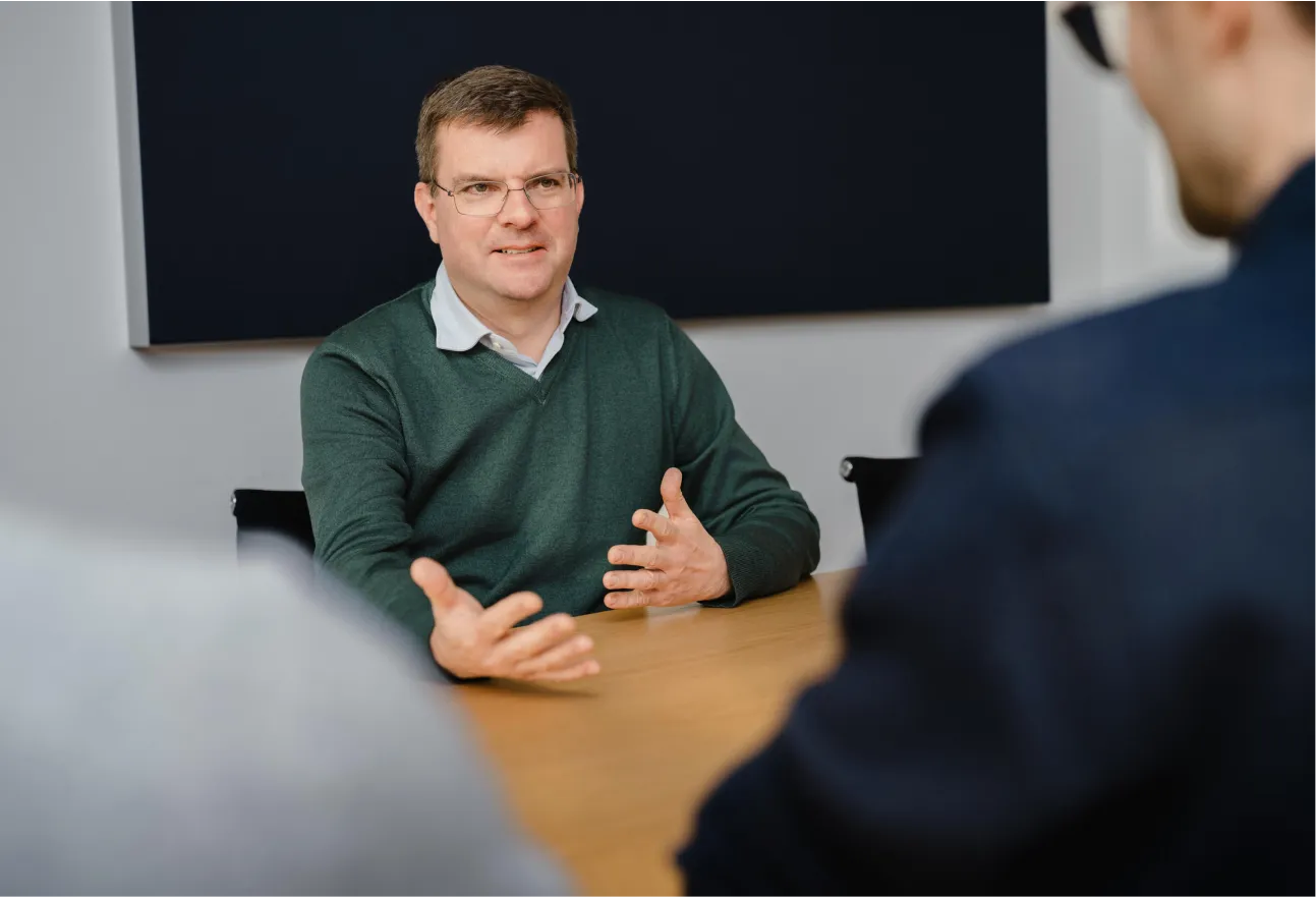 A man sitting at a table talking to another man.