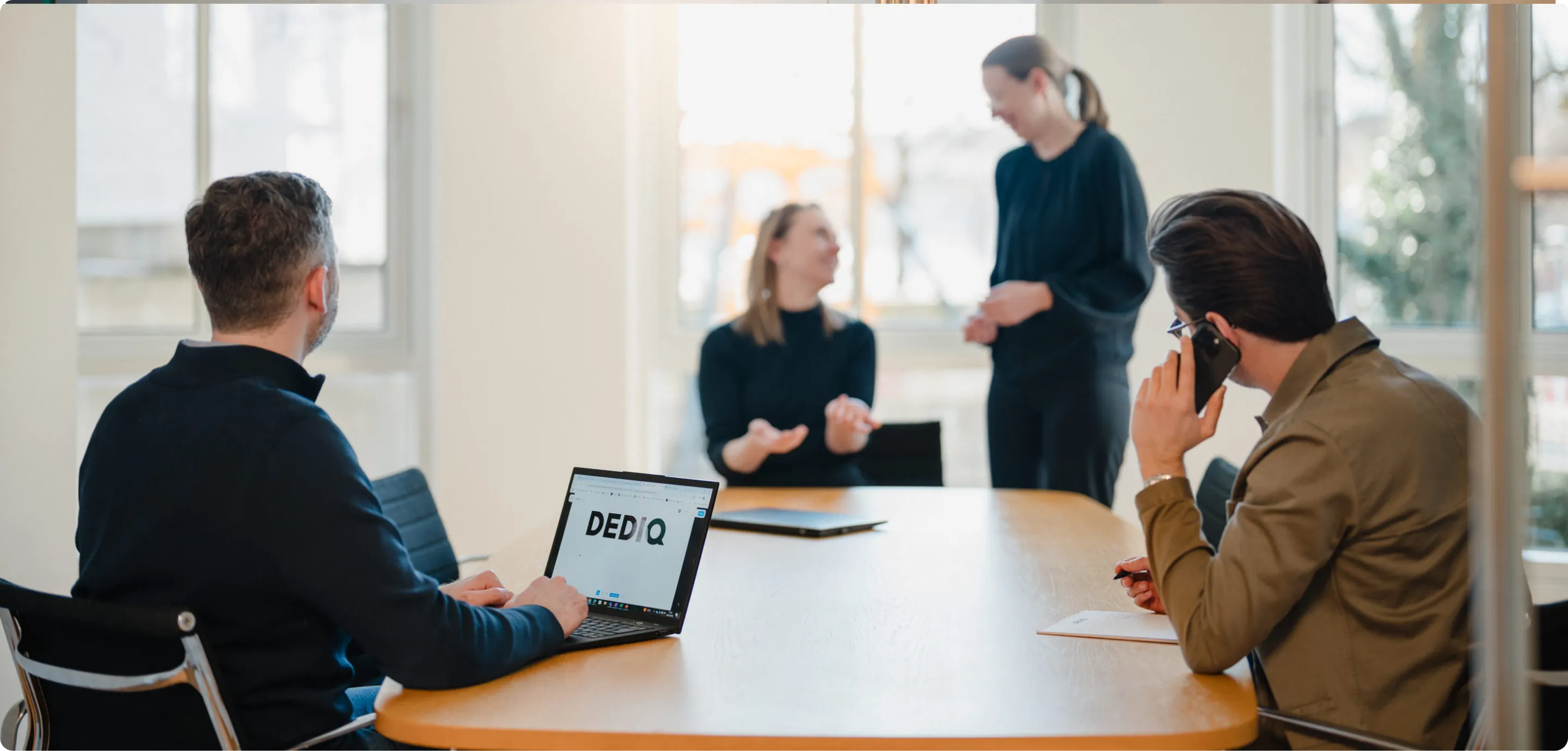 A group of people sitting around a wooden table.