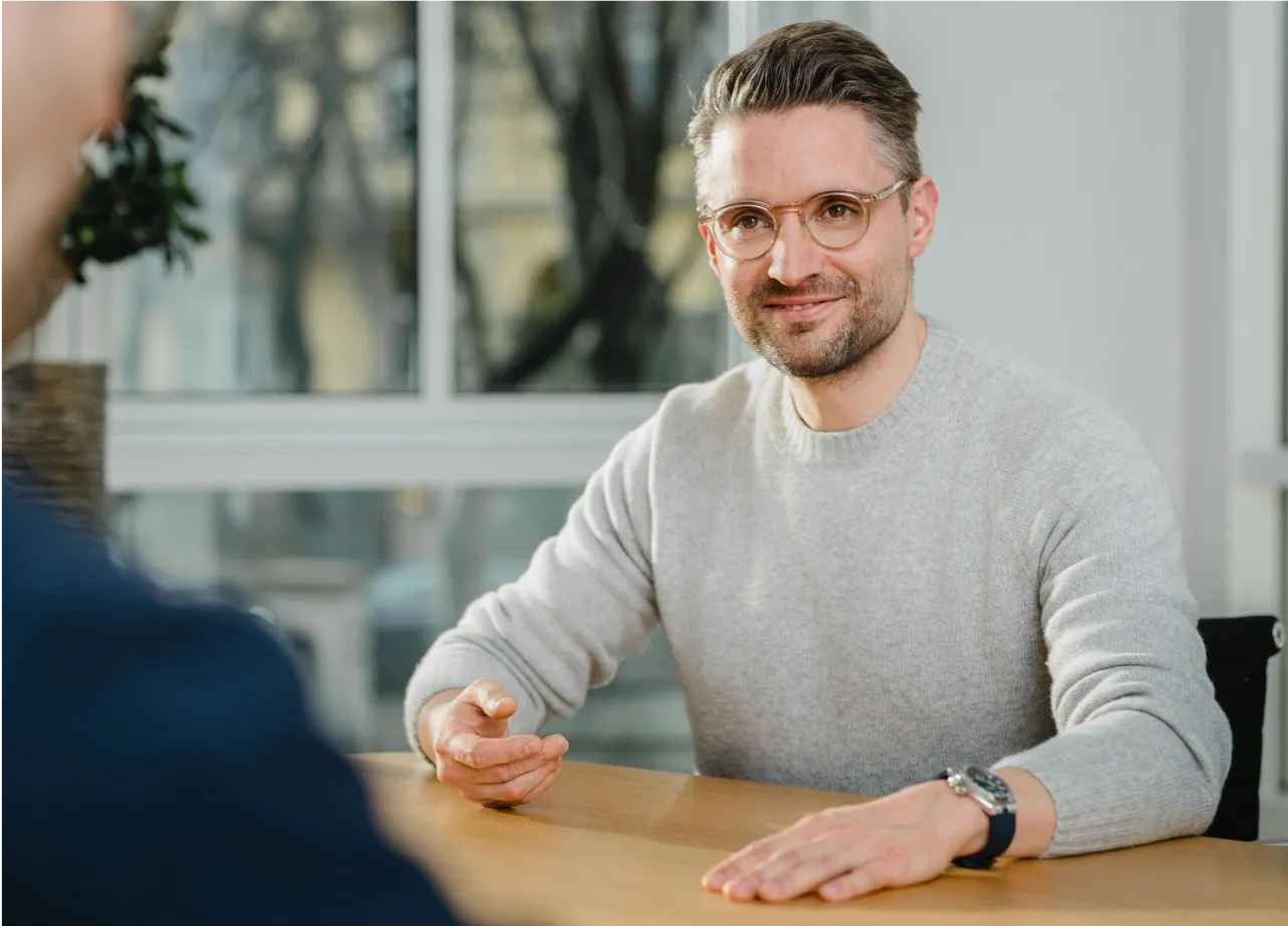 A man sitting at a table talking to another man.