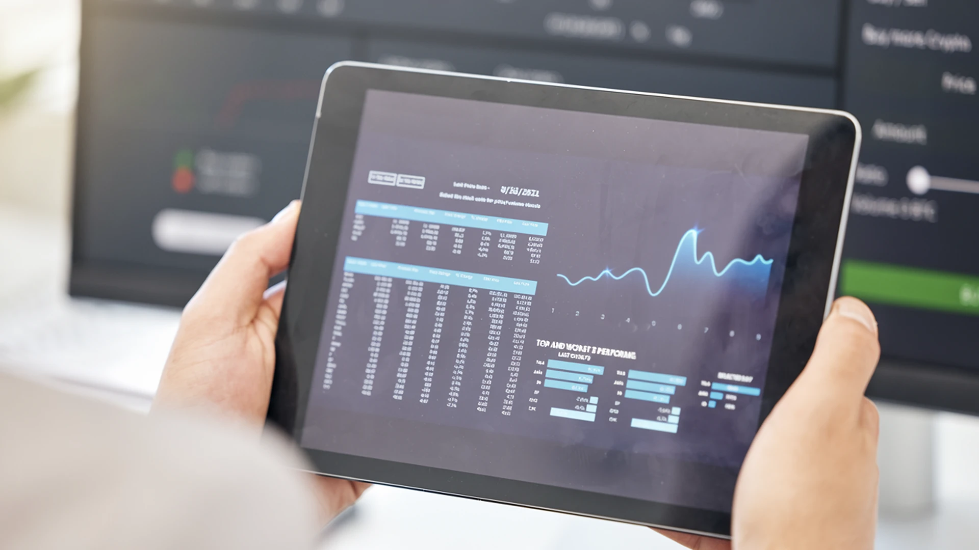 Person holding a tablet displaying digital financial data and a fluctuating line graph.