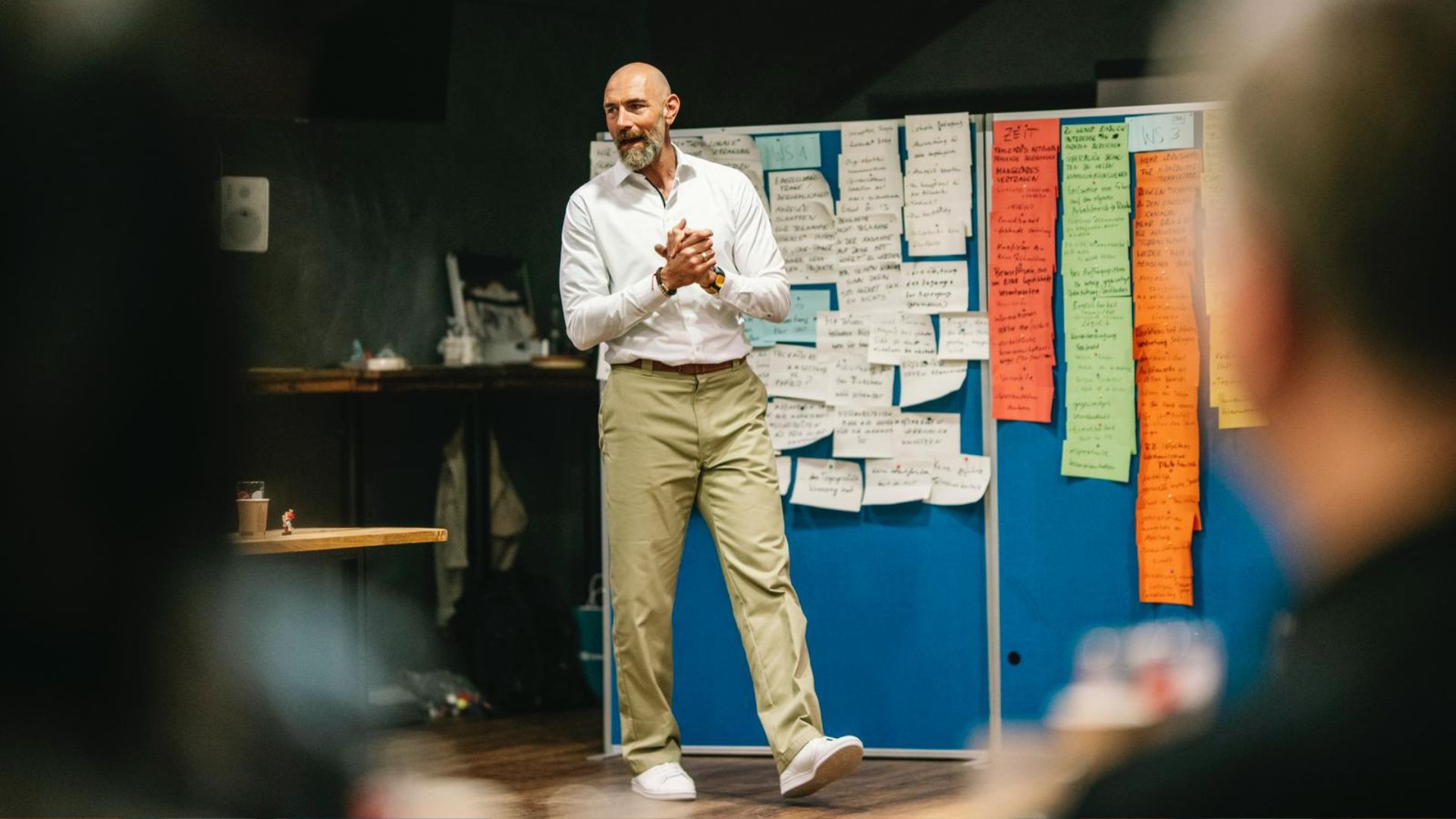 Mann hält Vortrag vor Pinnwand mit Notizzetteln und spricht zu einer Gruppe