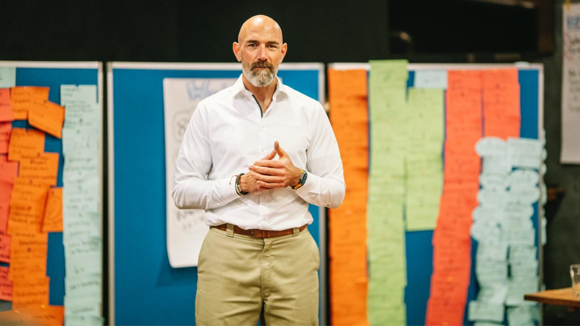 Mann steht vor Pinnwand mit bunten Notizzetteln und erklärt konzentriert Inhalte