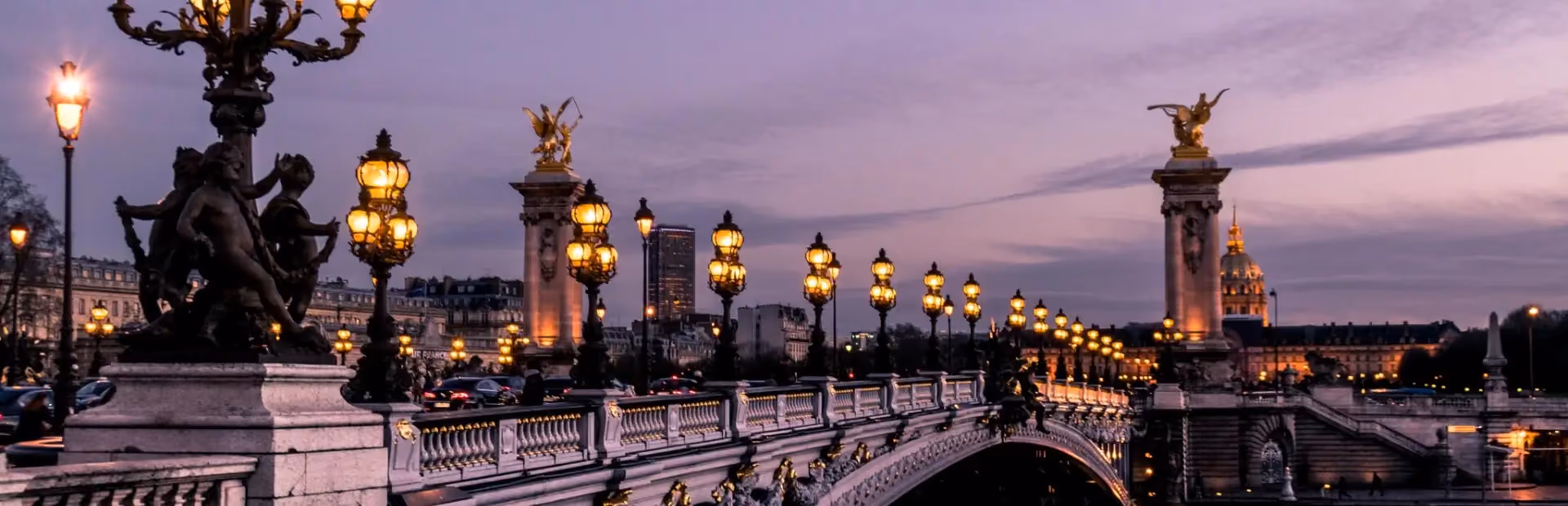 Pont Alexandre III à Paris illuminé au crépuscule avec lampadaires allumés et dôme des Invalides