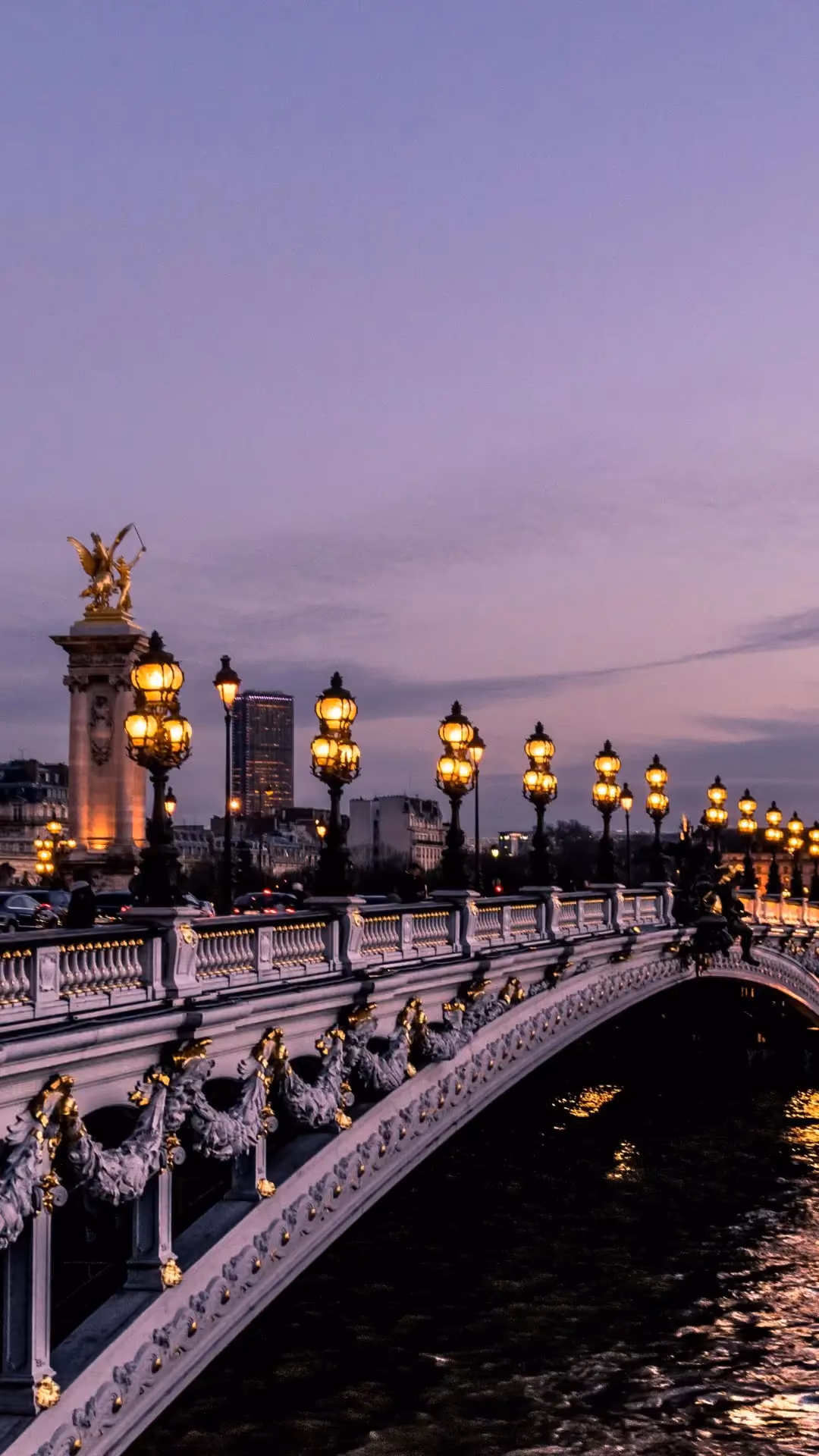 Pont Alexandre III à Paris illuminé au crépuscule avec lampadaires allumés et dôme des Invalides