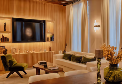 Salon de luxe moderne avec mur en lattes de bois, canapé blanc, fauteuil en velours vert et éclairage chaleureux.