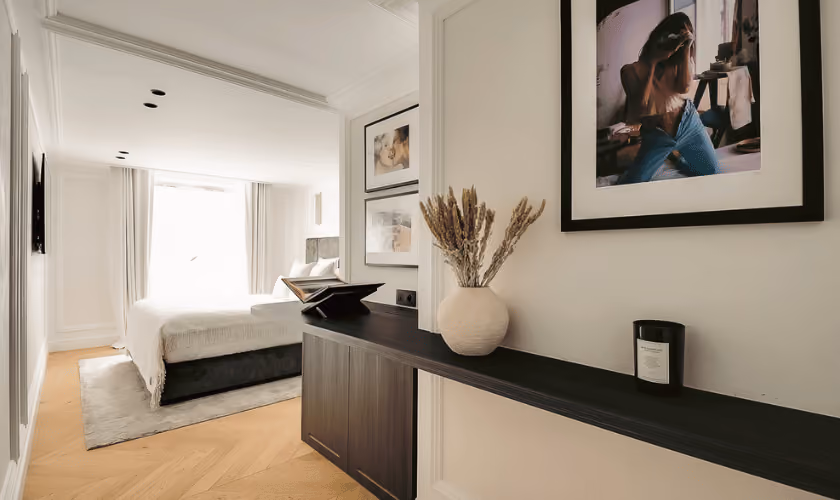 Chambre moderne et lumineuse vue depuis un couloir avec console.