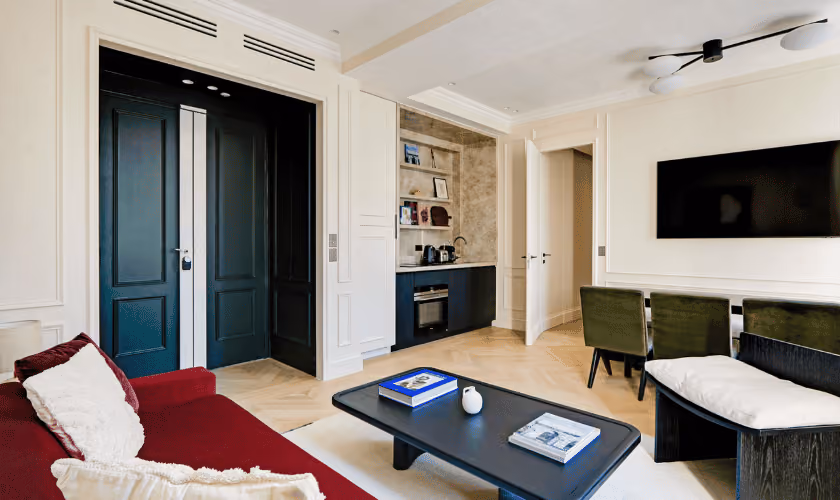 Salon moderne et élégant avec un canapé rouge vif, une table basse noire et des portes doubles sombres.