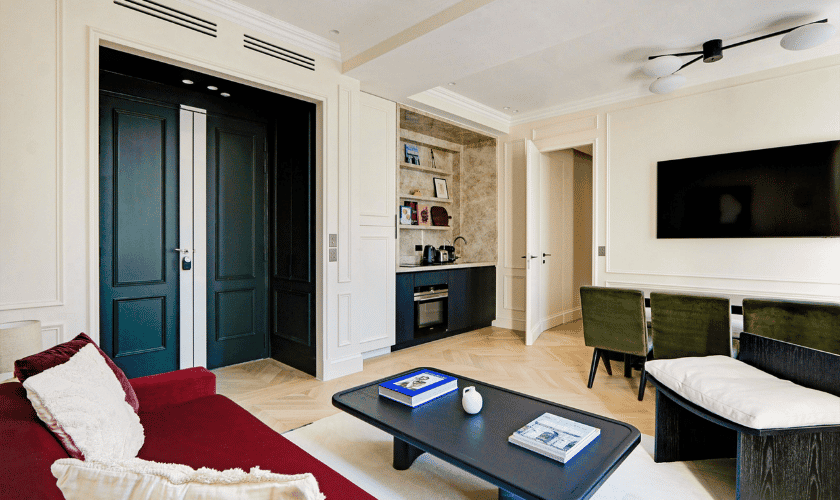 Salon moderne et élégant avec un canapé rouge vif, une table basse noire et des portes doubles sombres.
