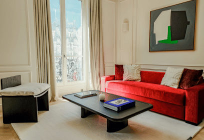 Modern apartment-style suite at The Lander Hotel featuring elegant contemporary design with large windows overlooking the iconic Parisian buildings.