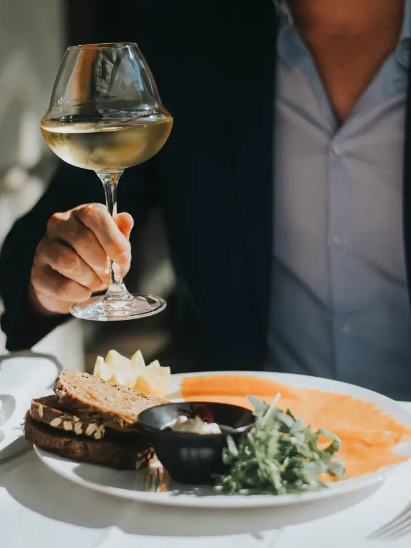 Photo of a man on the terrace of Bar 1807 at the Hôtel Napoléon Paris eating a plate of petrossian smoked salmon, a glass of white wine in hand