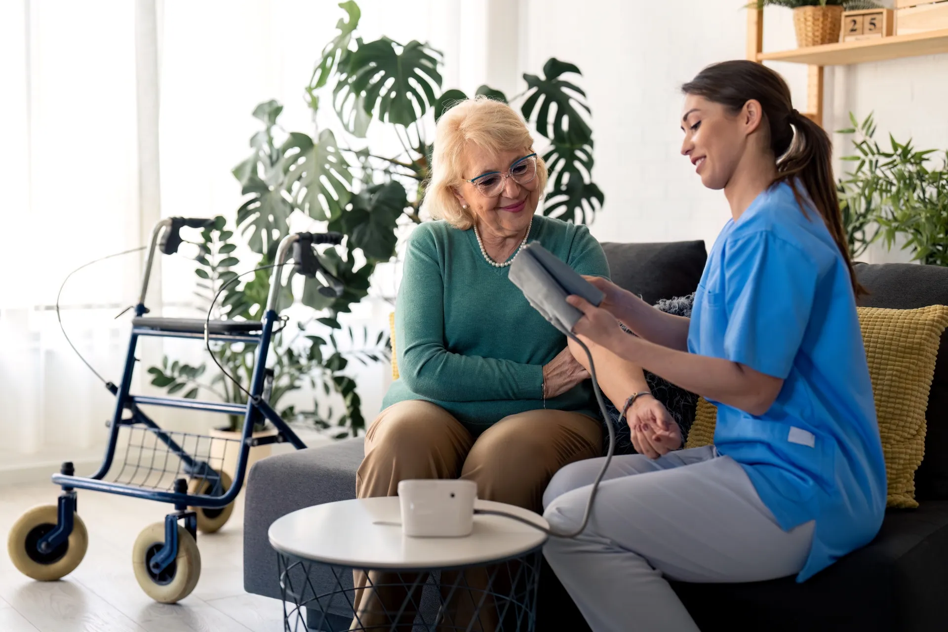 A woman sits on a couch with a nurse, engaged in a conversation in a comfortable indoor setting.