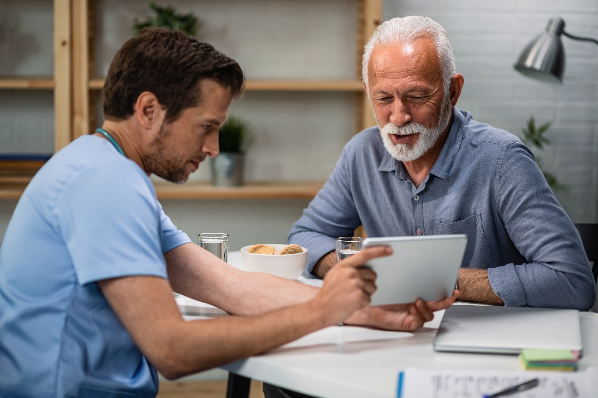 Doctor showing medical test results on a tablet to a smiling senior male patient during a consultation