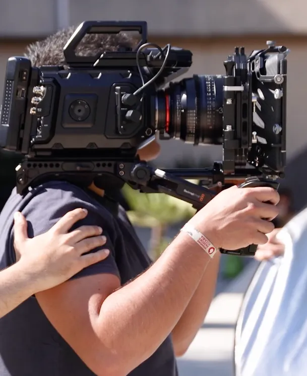 Aluno a fazer uma filmagem em movimento com maquina de filmar ao ombro