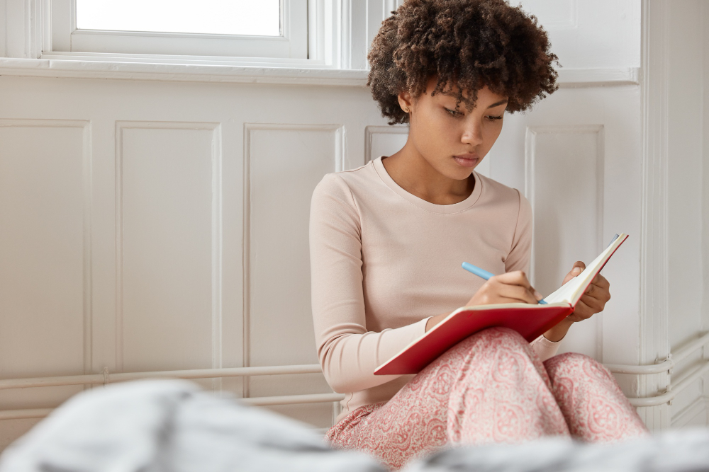woman writing on a book - Is Geography A Level Hard