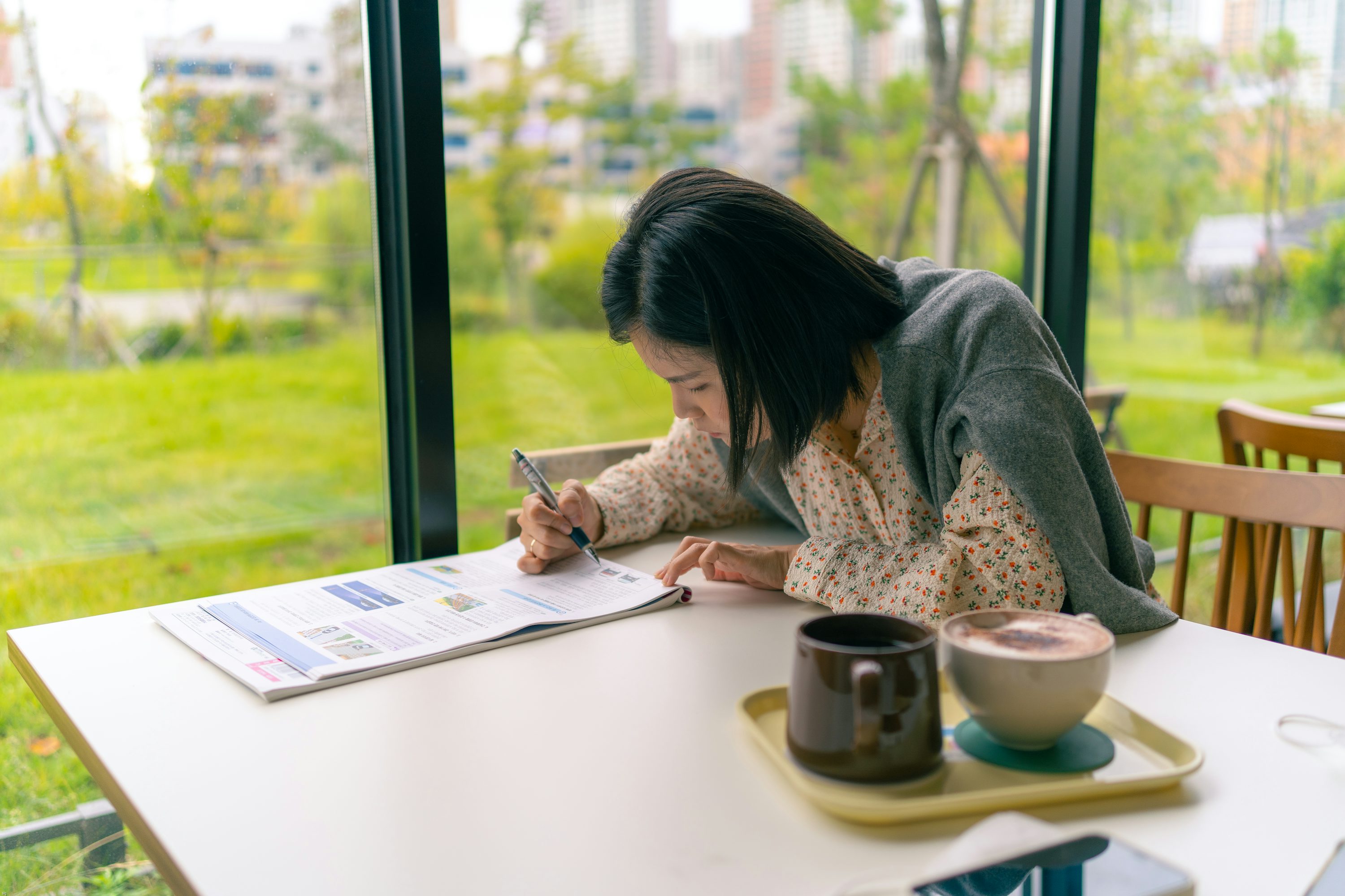 a woman sitting at a table writing on a piece of paper - How to Revise A Level Biology	