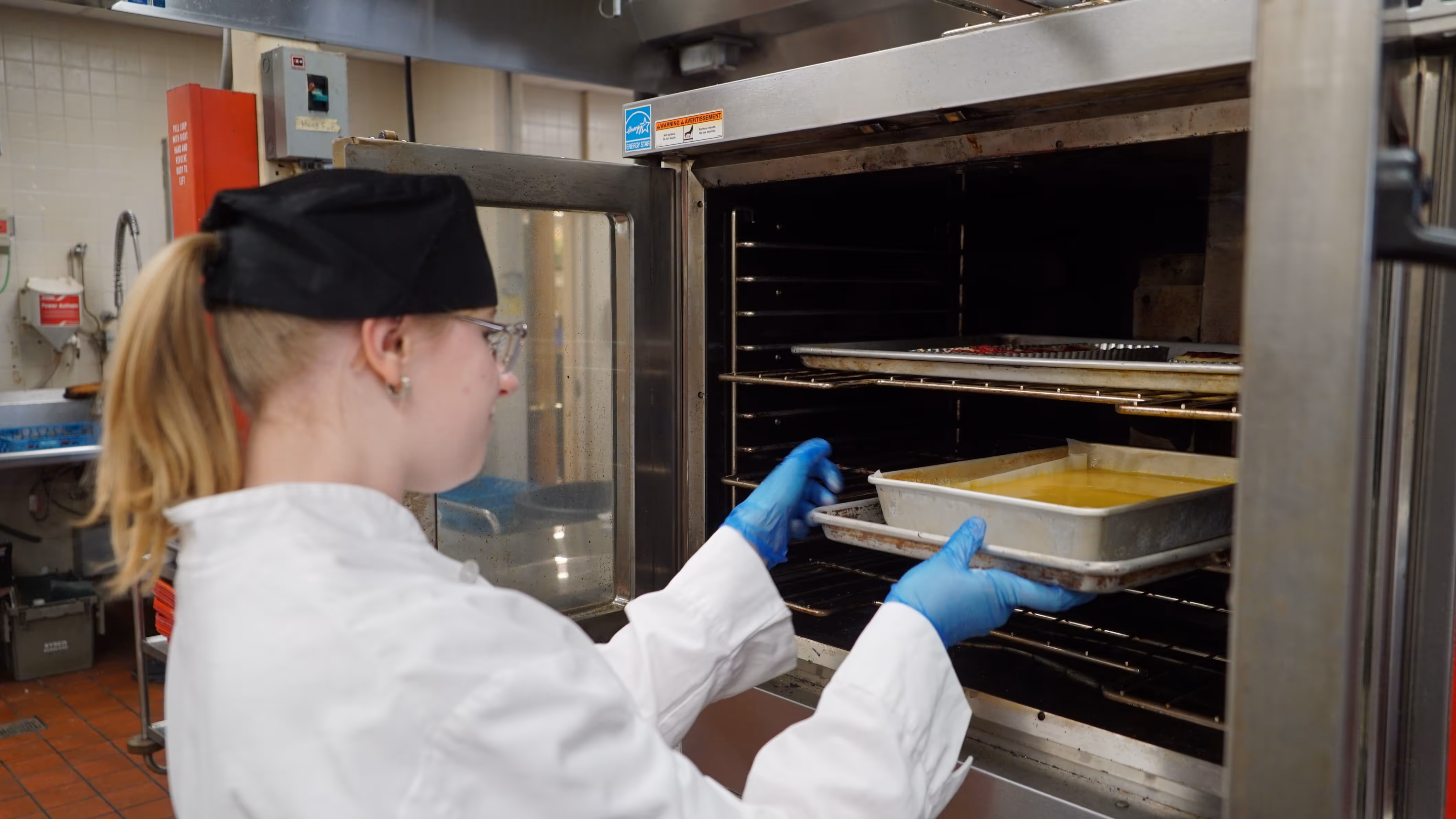 Student putting bread in oven.
