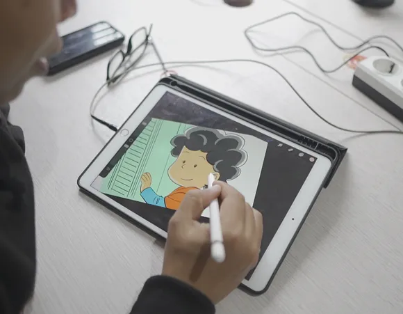 Person using a stylus to draw a cartoon character with curly hair on a tablet.