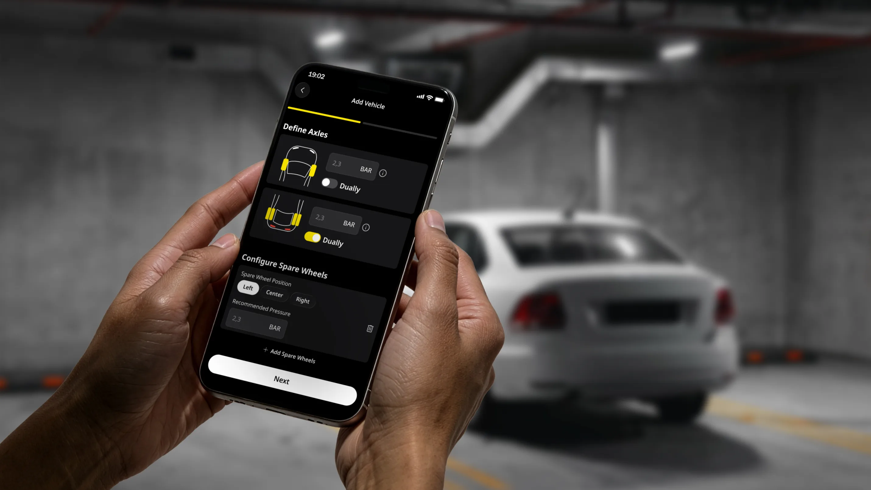 Main tenant un téléphone devant sa voiture.