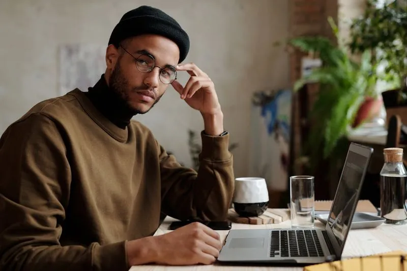 A man sitting at a table in front of a laptop computer.
