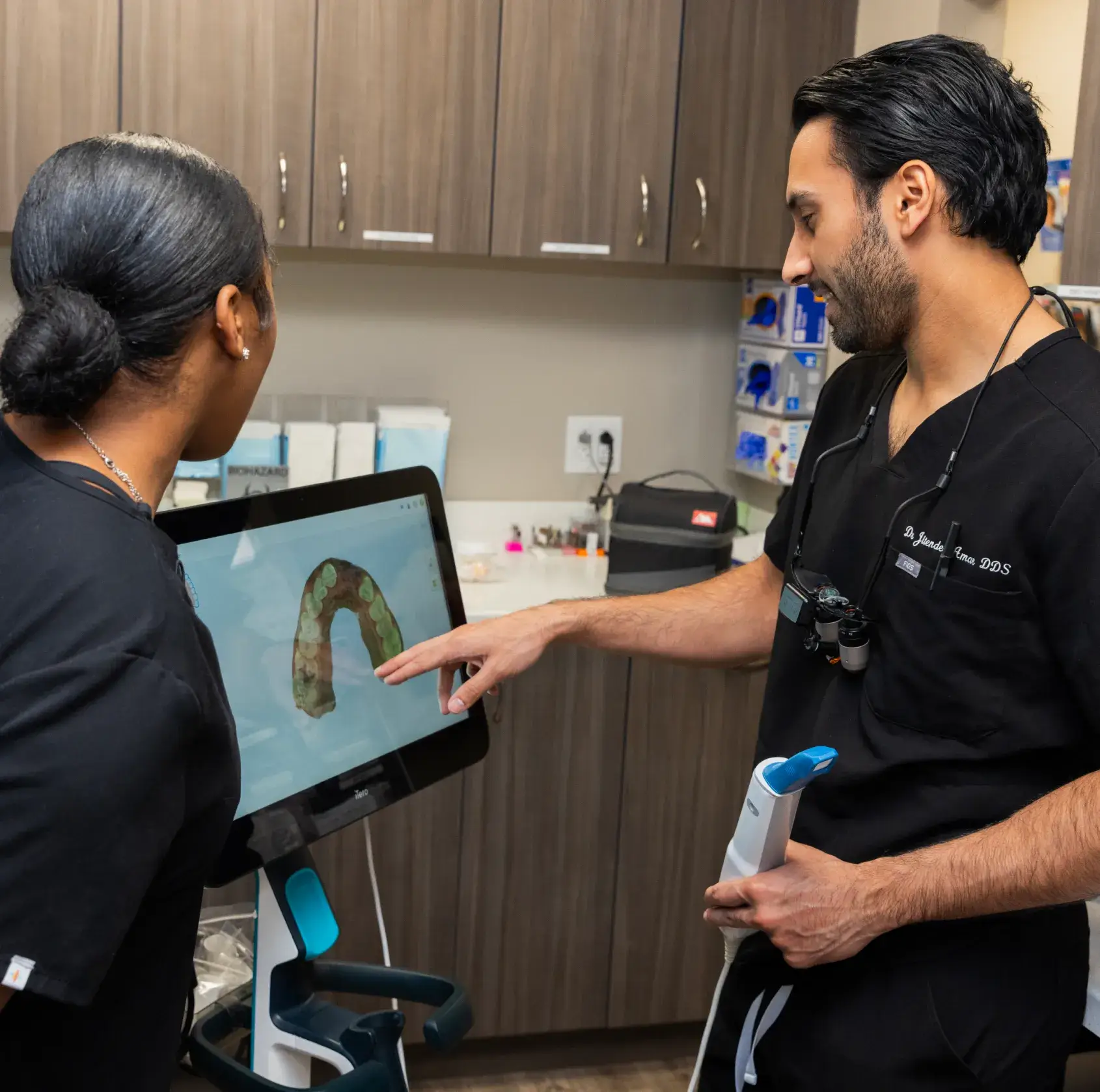 Two dental professionals discuss a dental scan on a monitor in a clinic.